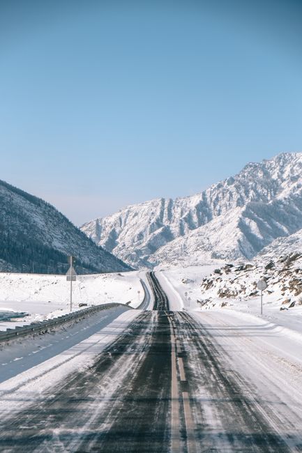 Beautiful snowcapped road in Altay Mountains, showcasing a clear winter day.