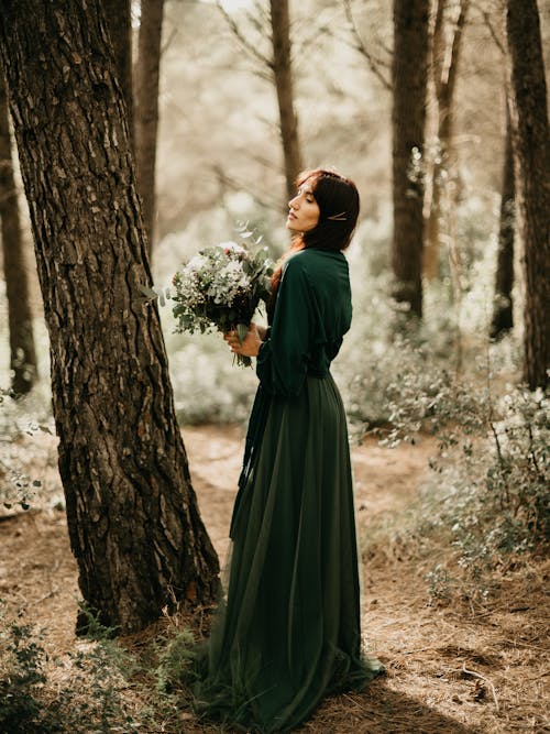 Woman in Dress and with Flowers in Forest