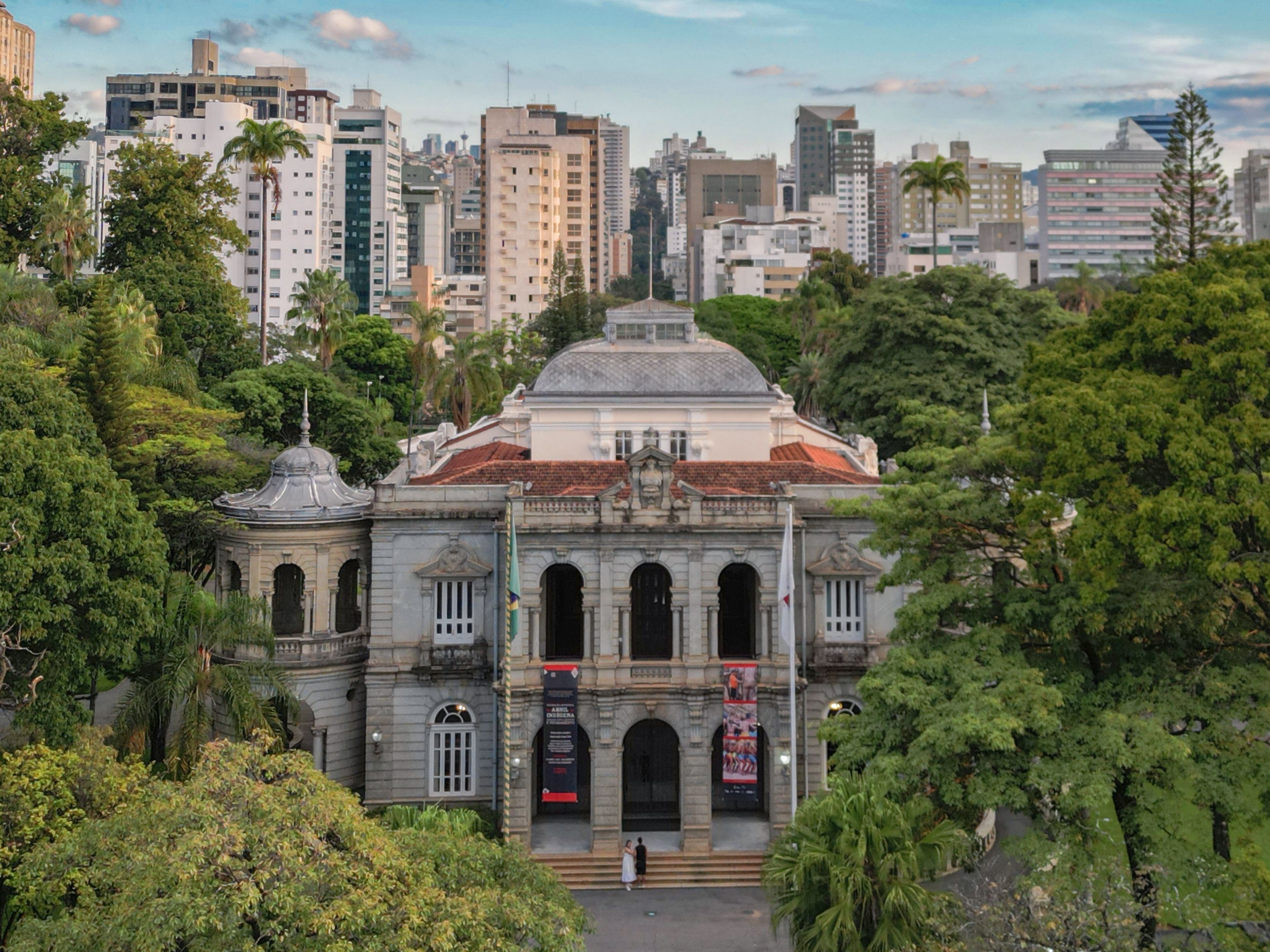 Elegant view of the Palace of Liberty surrounded by lush trees and modern skyline in Belo Horizonte, Brazil.