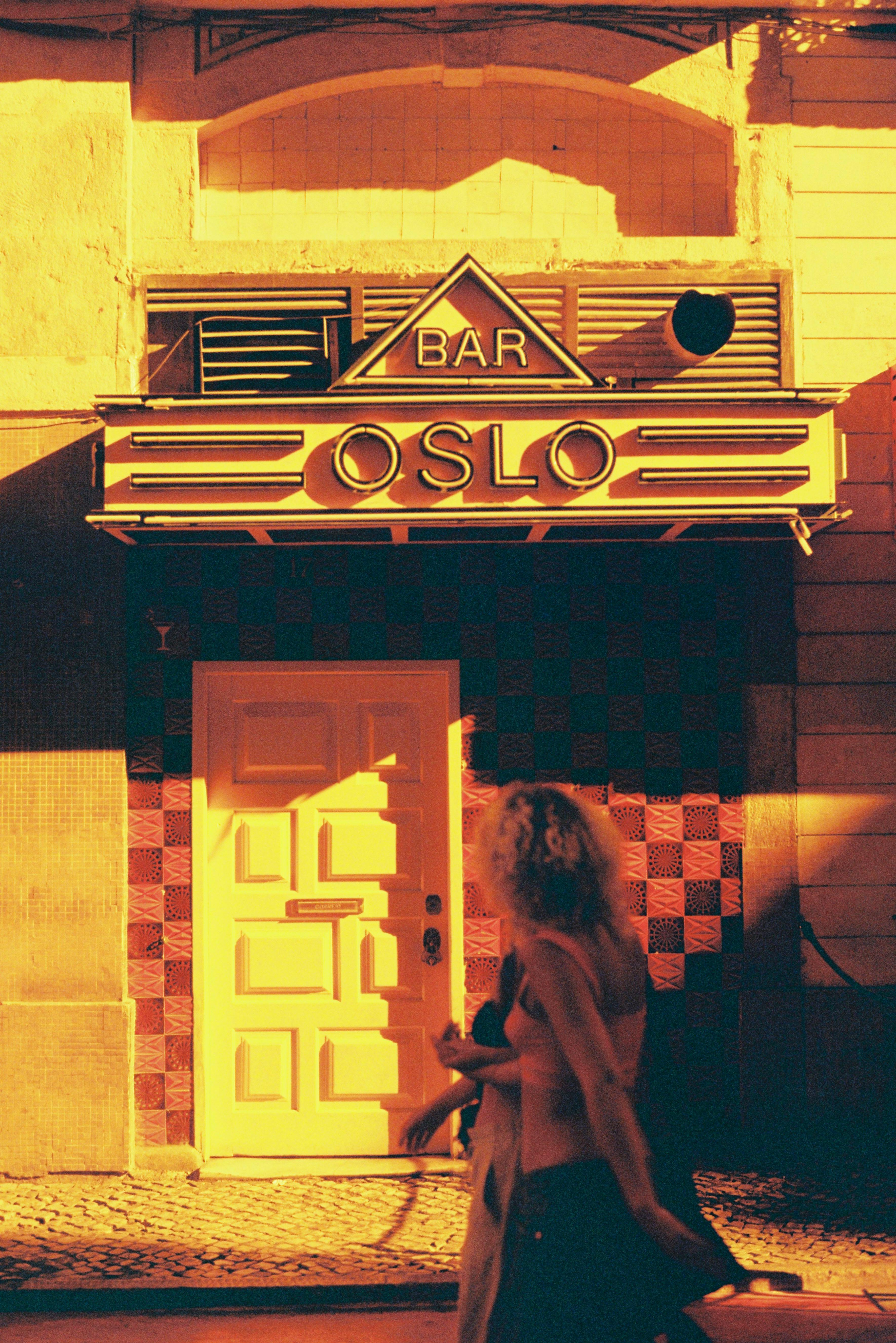Vintage style photograph of Bar Oslo facade with a walking woman in Lisbon.