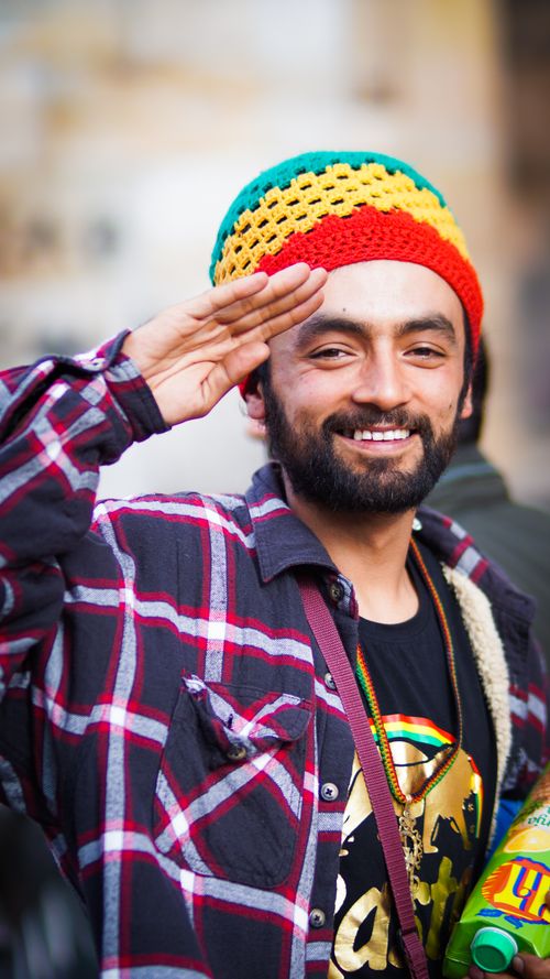 Free Cheerful man in checkered shirt and colorful hat saluting outside in Bogotá, Colombia. Stock Photo