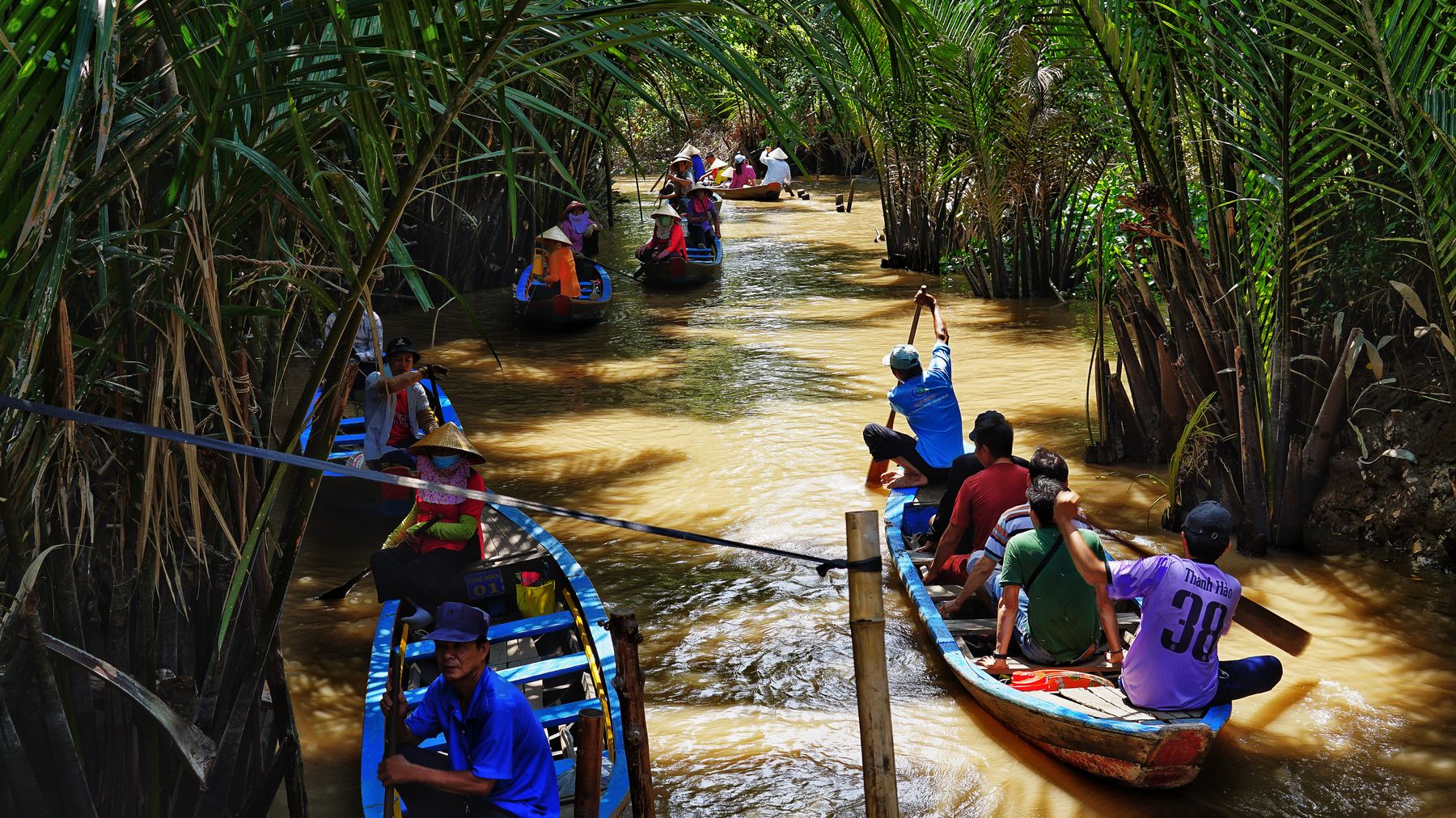 People kayaking through lush palm-fringed canals in Vietnam's Mekong Delta.