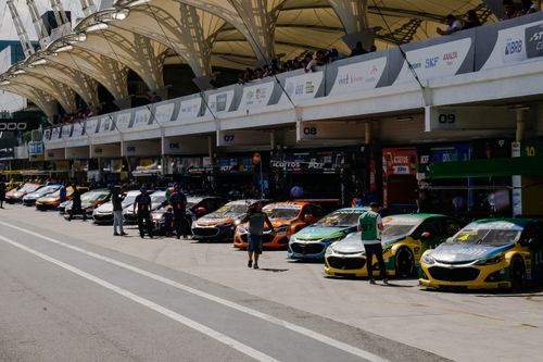 Free Stock cars lined up at the circuit garage during a sunny racing event. Stock Photo