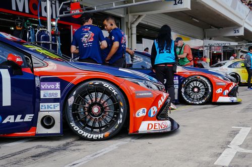 Free Close-up of colorful race cars in a pit stop with mechanics and crew preparing for a motorsport event. Stock Photo