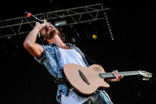 Man Using Brown and Black Electric Guitar While Singing