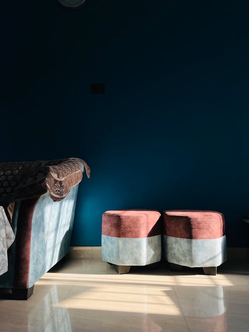A blue room with two stools and a lamp