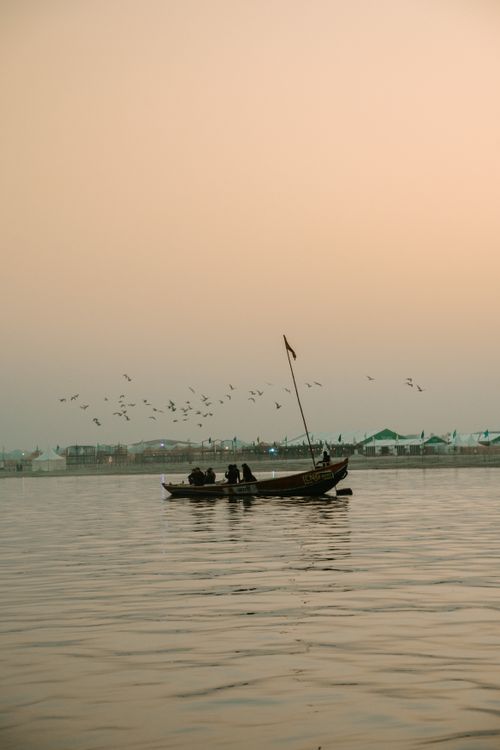 Free A tranquil boat ride at sunset on an Indian river, with birds flying in the sky. Stock Photo