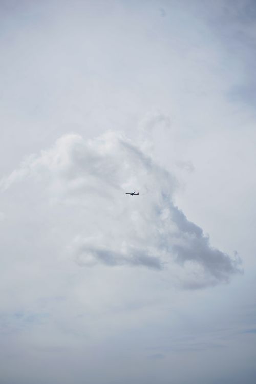 Free A small airplane flies across a vast sky with large, dramatic clouds, capturing the essence of travel and freedom. Stock Photo