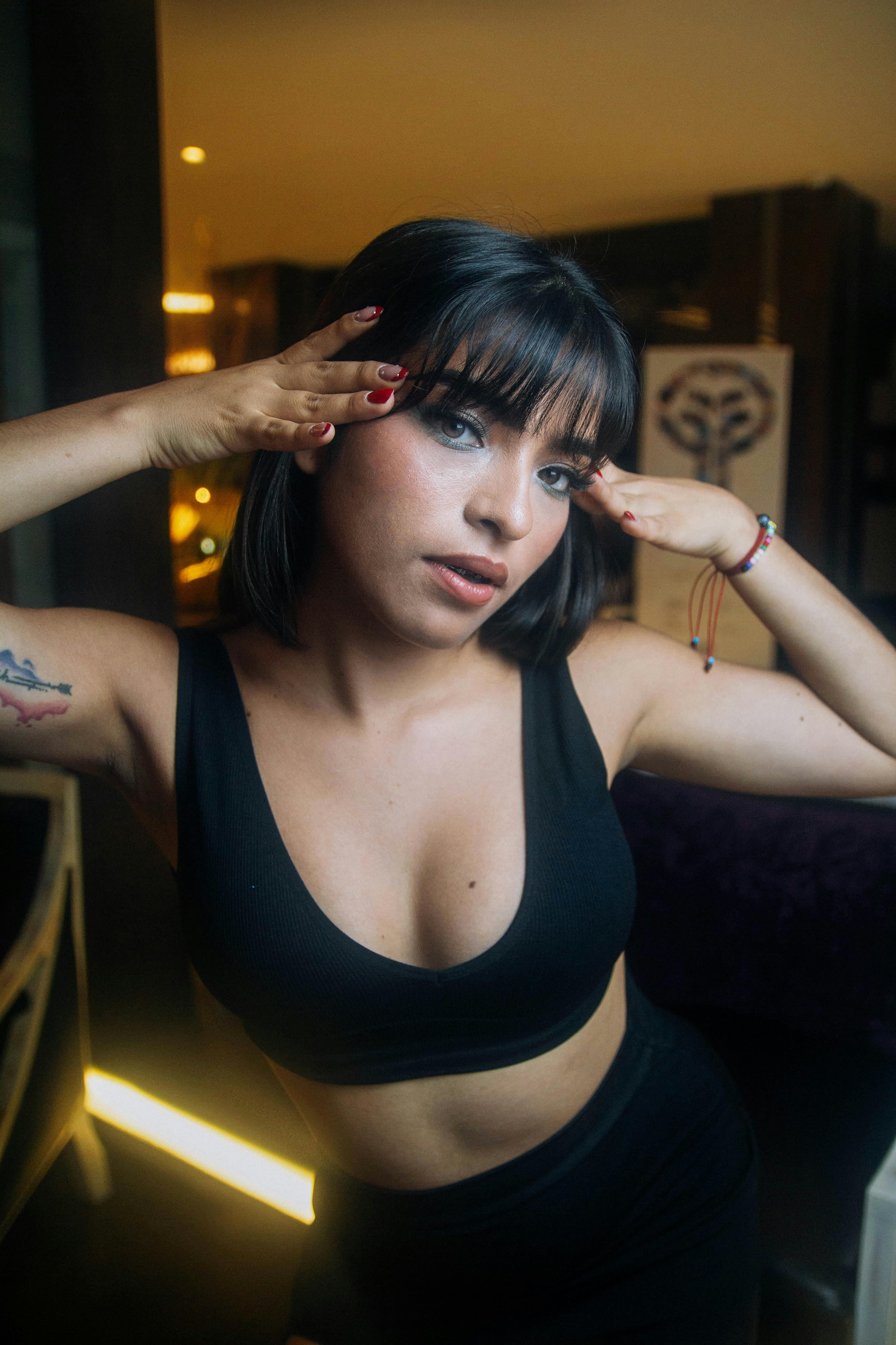 Stylish young woman with tattoos striking a pose indoors, showcasing a trendy look.