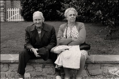 Free Elderly couple seated on a stone wall enjoying a day outside. Stock Photo