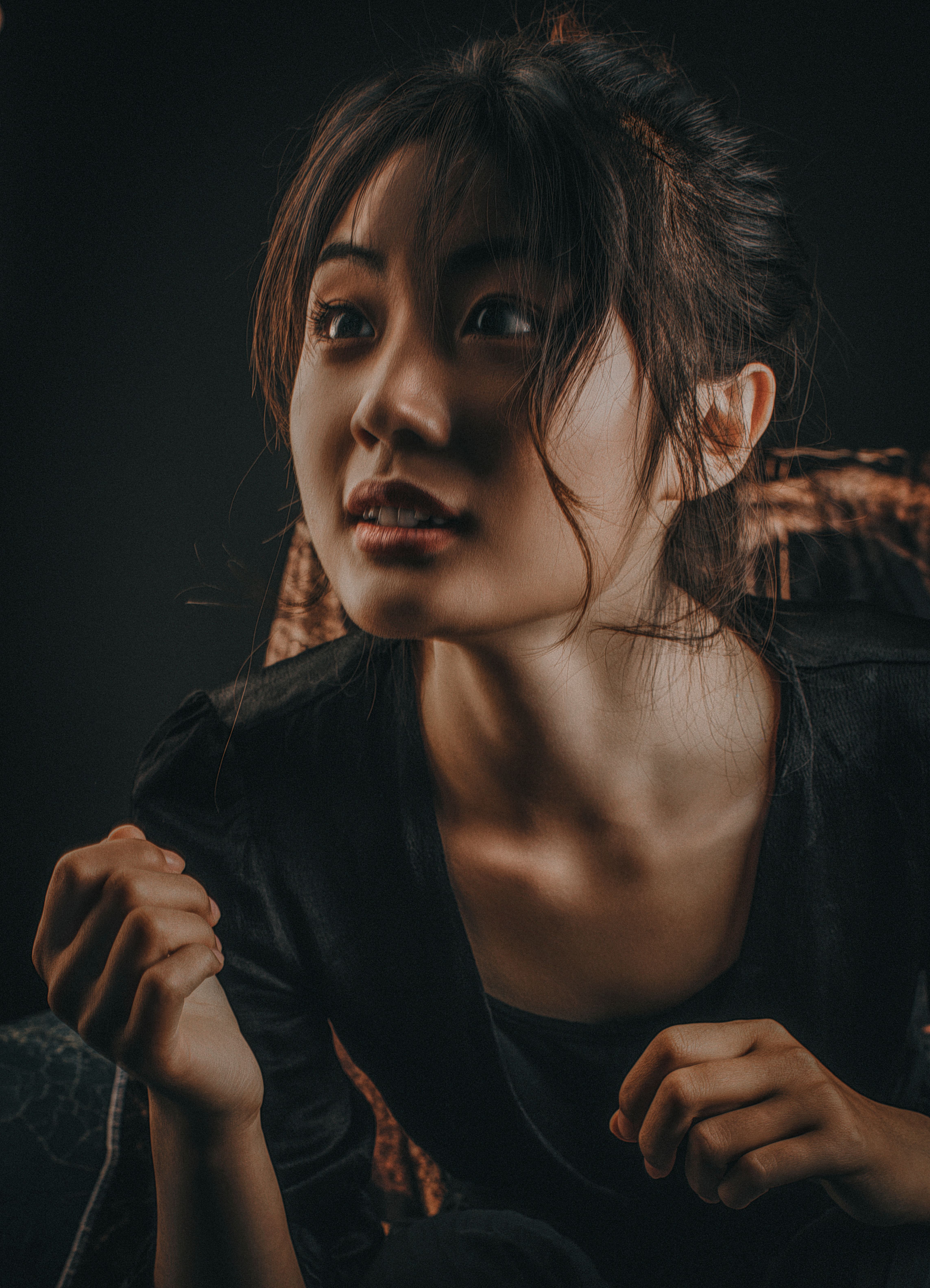 A captivating portrait of an Asian woman with a moody, dramatic lighting on a dark background.