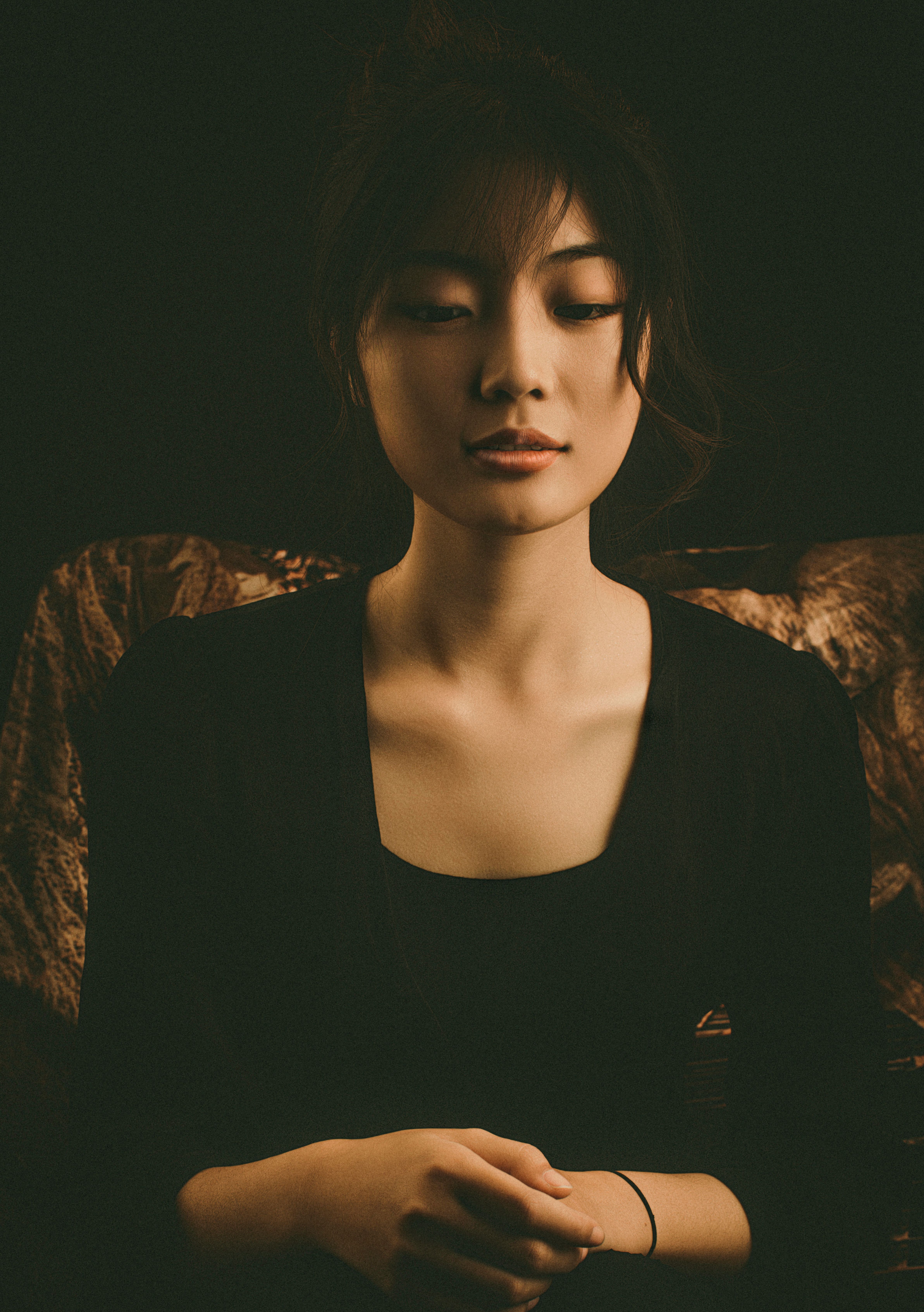 A serene, elegant portrait of a young woman in a black outfit with a moody tone.