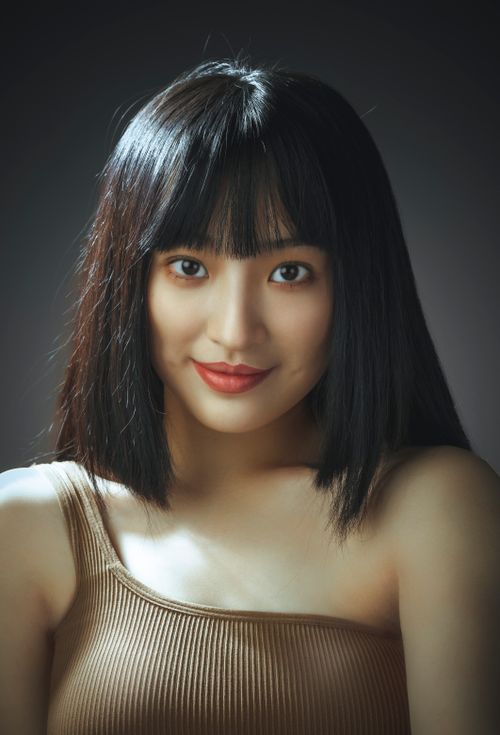 Free Studio portrait of a young woman with bangs, smiling softly, in a neutral background. Stock Photo