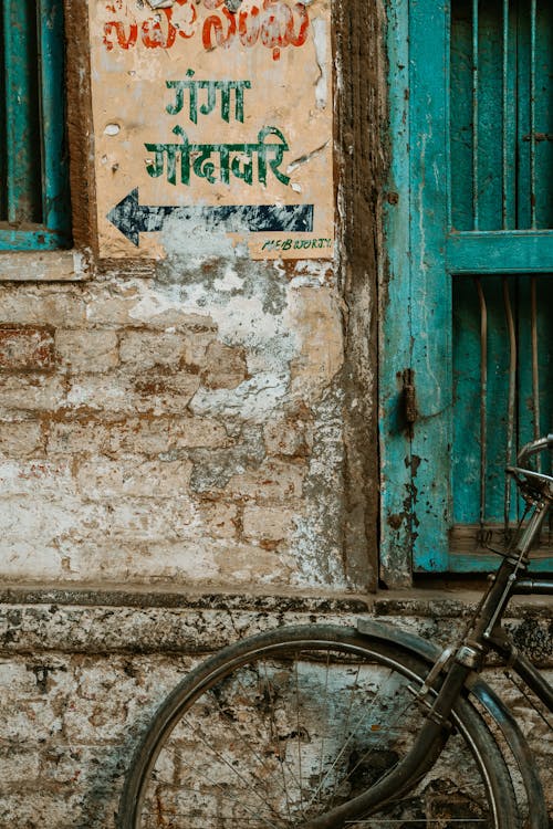 Old Bicycle left against a Shabby Wall with a Sign 