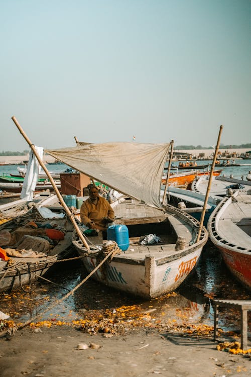 Fisherman Sitting in a Fishing Boats Moored on a Beach 