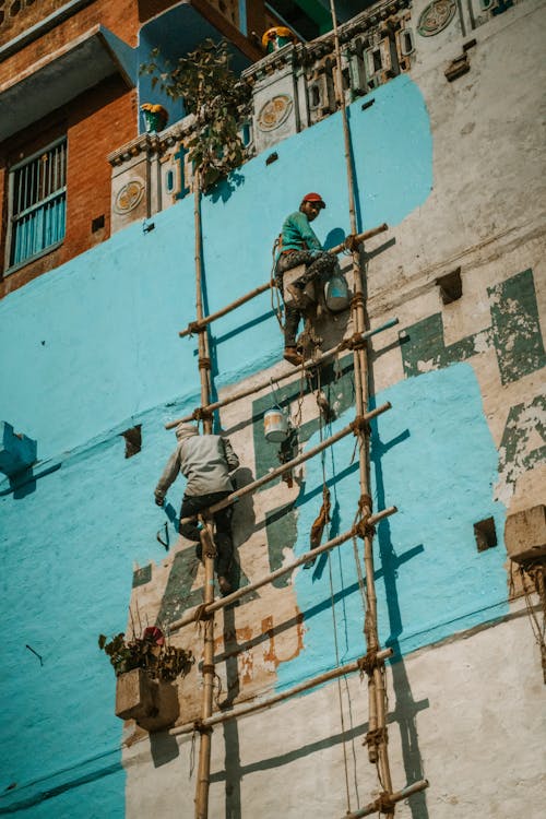 Workers Painting the Facade of a Building on Improvised Scaffolding