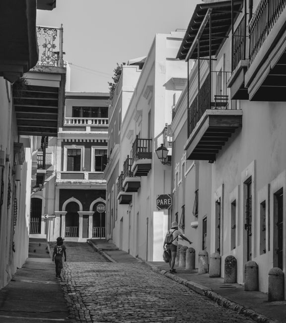 Black and white photograph of a cobblestone street in historic San Juan with classic architecture.