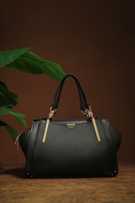 Stylish black handbag showcased with green leaves against a brown backdrop, perfect for fashion themes. - quality ladies handbags