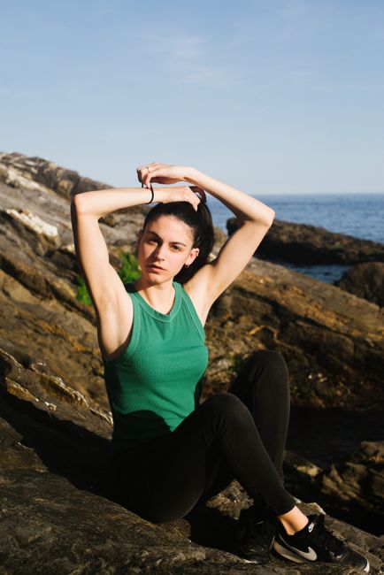 Young woman relaxing at rocky beach in Genoa, Italy with ocean view.