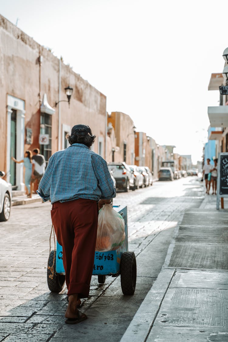 Man Pushing A Cart In A Town Street 