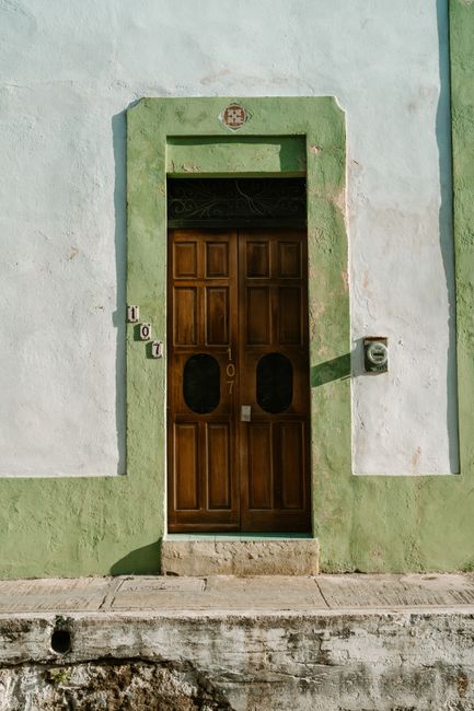 An inviting wooden door framed in green, typical architecture of a Mexican town.