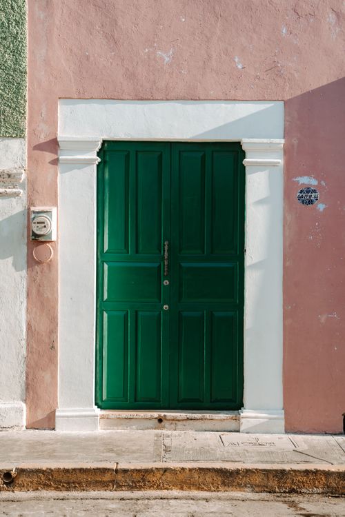 Free A vibrant green door on a colorful Mexican townhouse facade captures urban charm. Stock Photo