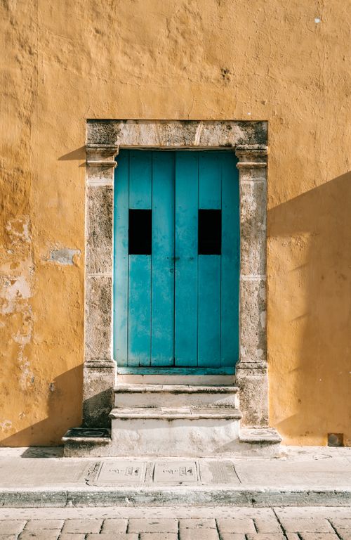 Free A vibrant blue door on a rustic townhouse facade in a Mexican town. Stock Photo