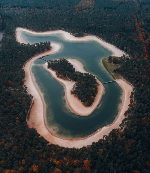 Free A stunning aerial view of a forest and a winding lake, surrounded by lush trees. Stock Photo