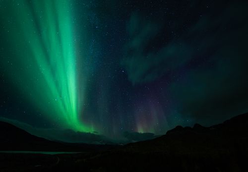 Free A stunning display of the aurora borealis illuminating the night sky with vibrant green and purple hues. Stock Photo
