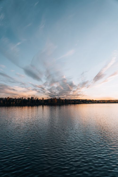 Free Peaceful evening view of a calm lake reflecting the sunset sky. Stock Photo