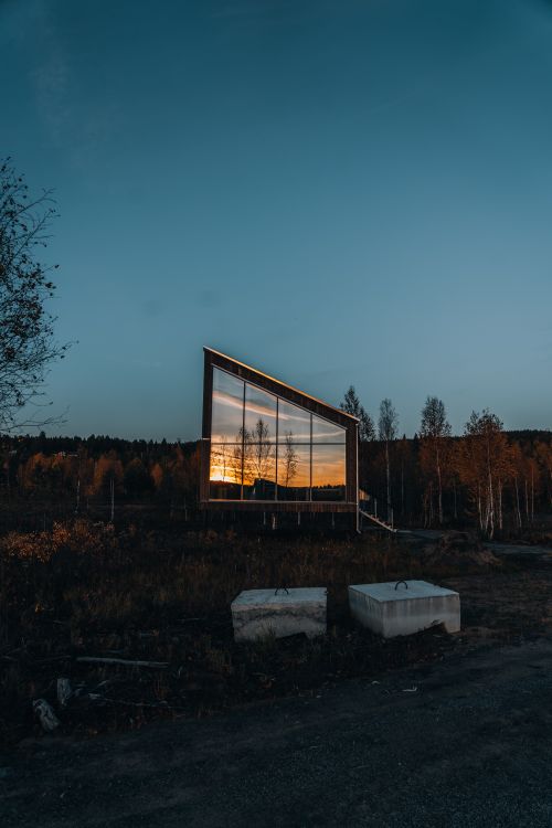 Free A modern building with glass reflection of sunset in a rural forest setting. Stock Photo