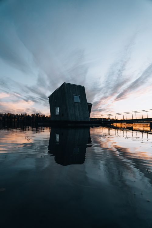 Free A stunning view of a wooden cabin by the lakeshore during twilight, reflecting a serene atmosphere. Stock Photo