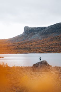 一位独自的徒步旅行者站在岩石上，俯瞰秋季宁静的山区湖泊。 - 相关推荐