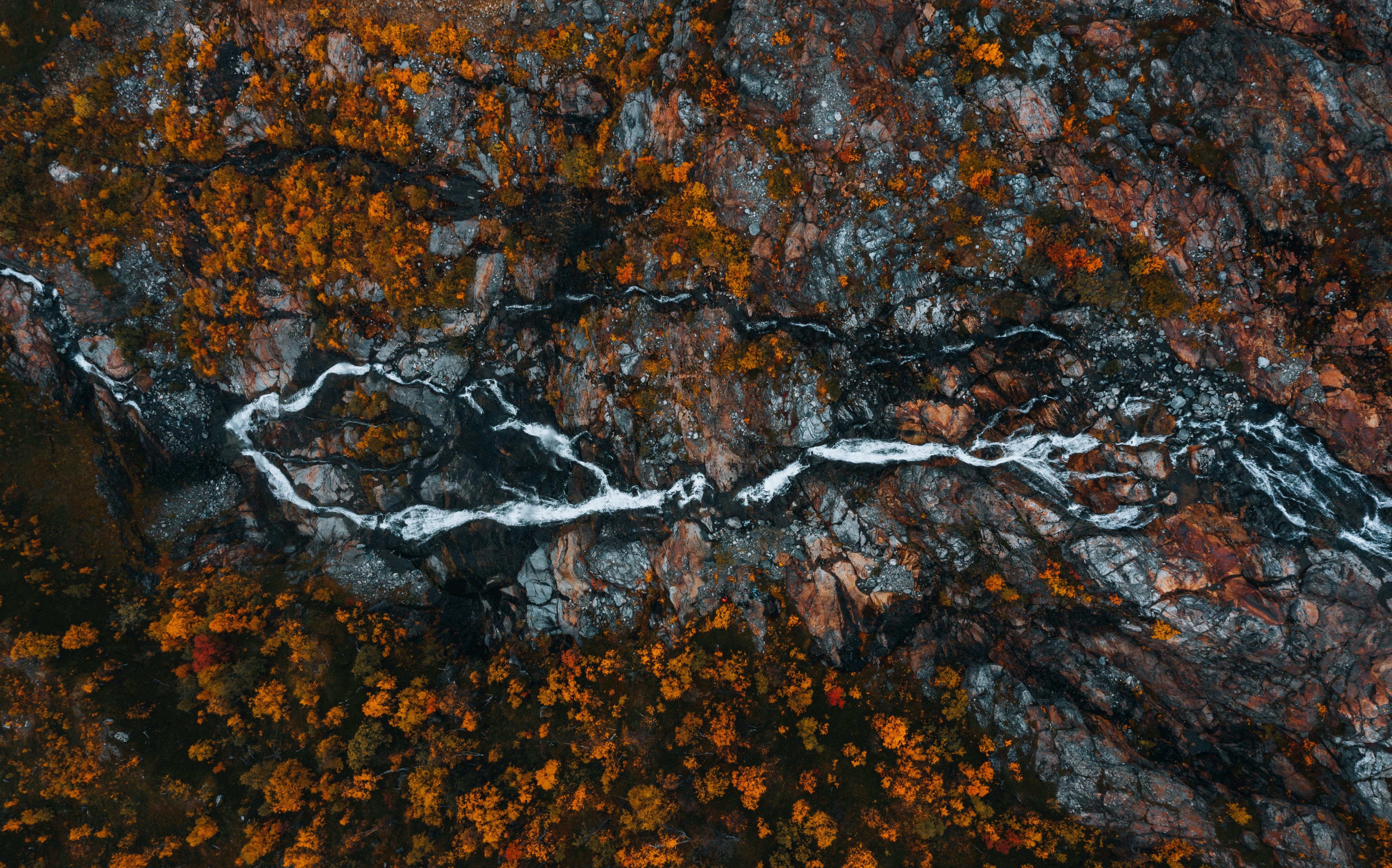 Aerial view of a rocky landscape with flowing stream and autumn foliage in Swedish Lapland.