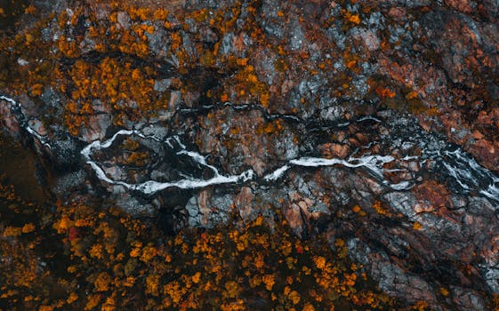 Aerial view of a rocky landscape with flowing stream and autumn foliage in Swedish Lapland.