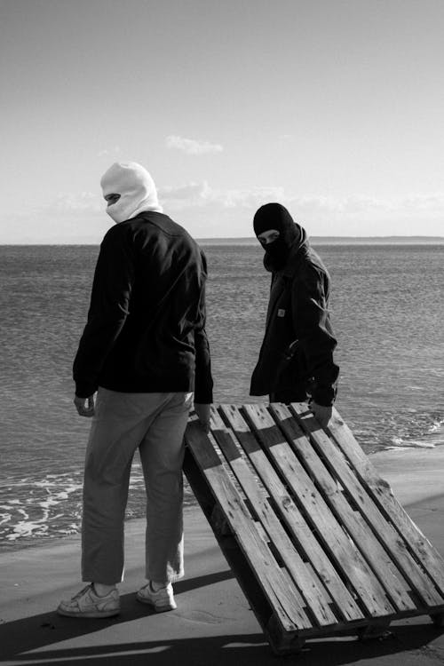 People in Balaclavas on the Beach in Black and White