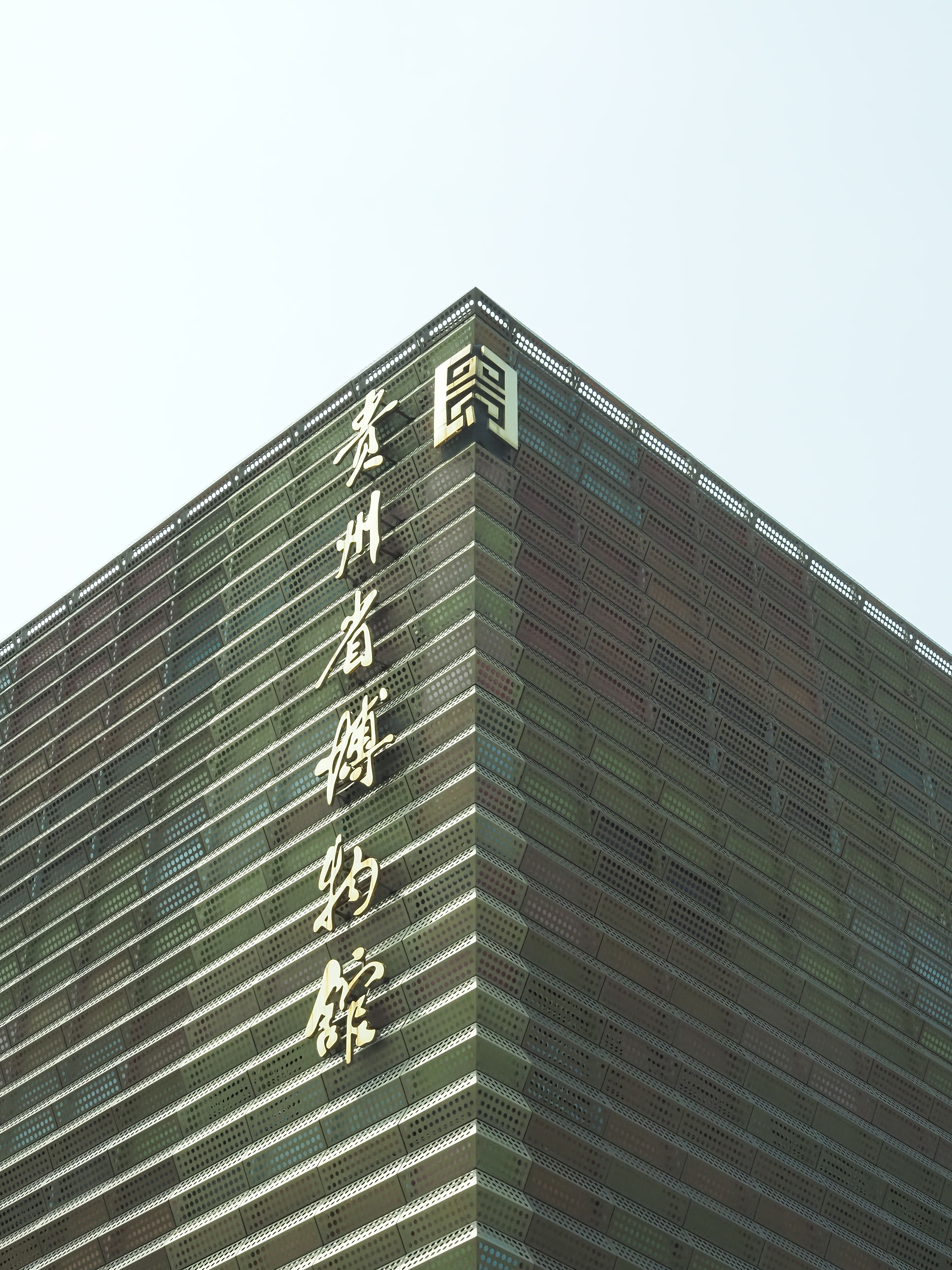 Contemporary urban building facade with geometric design and Asian characters.