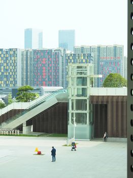 Cityscape with glass elevator, modern architecture, and people walking.