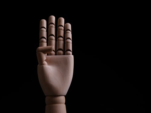 Free Artistic wooden mannequin hand against a black background, ideal for creative design projects. Stock Photo