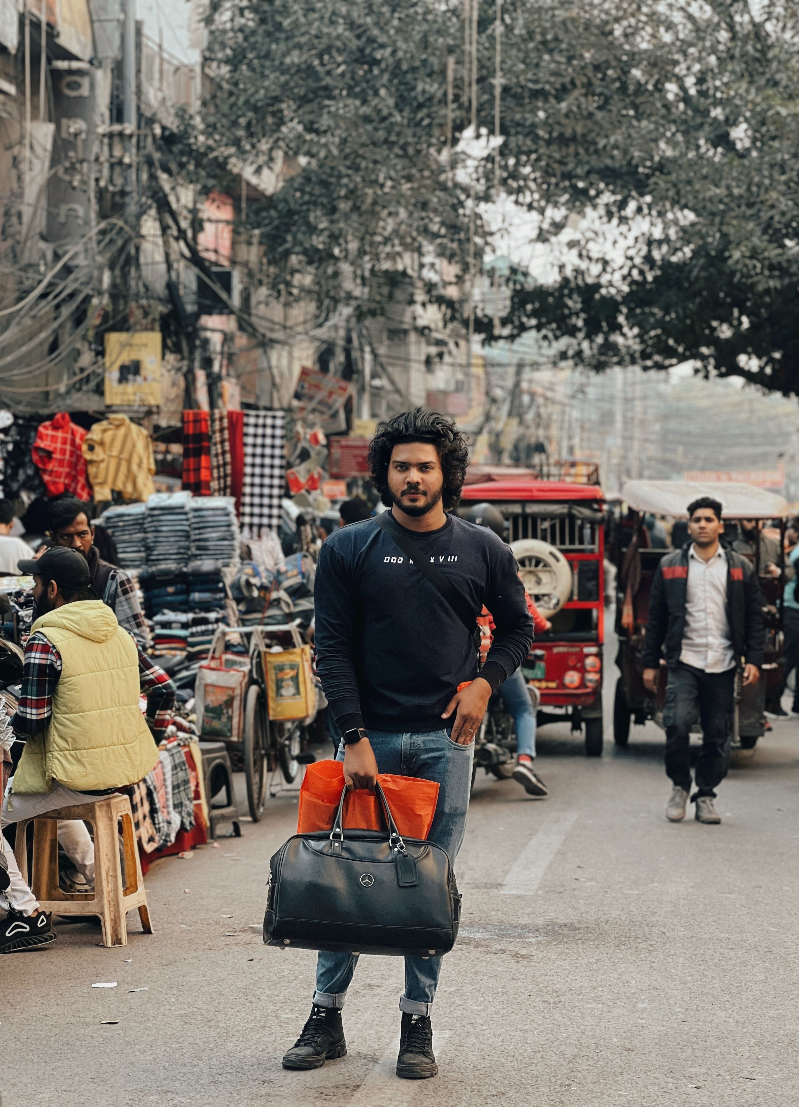 Man with bags stands confidently in a lively street market scene, showcasing urban casual style. - Local Brands and Where to Buy Them in Pakistan