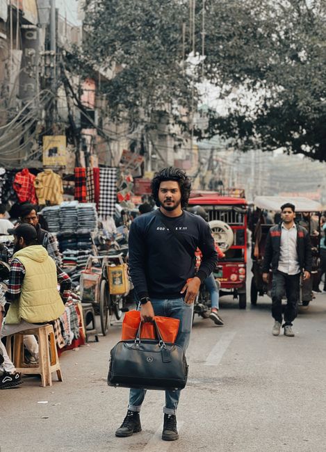 Man with bags stands confidently in a lively street market scene, showcasing urban casual style. - Local Brands and Where to Buy Them in Pakistan