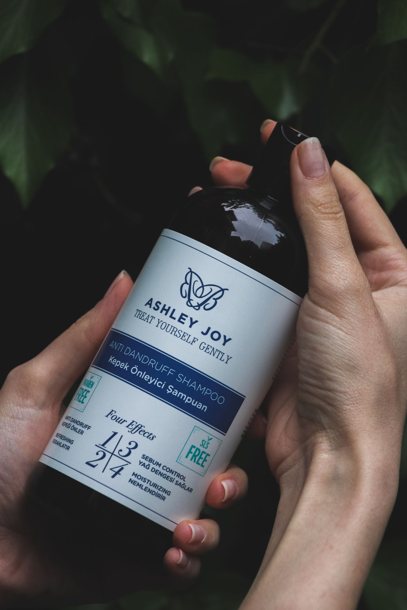 Hands holding an anti-dandruff shampoo bottle