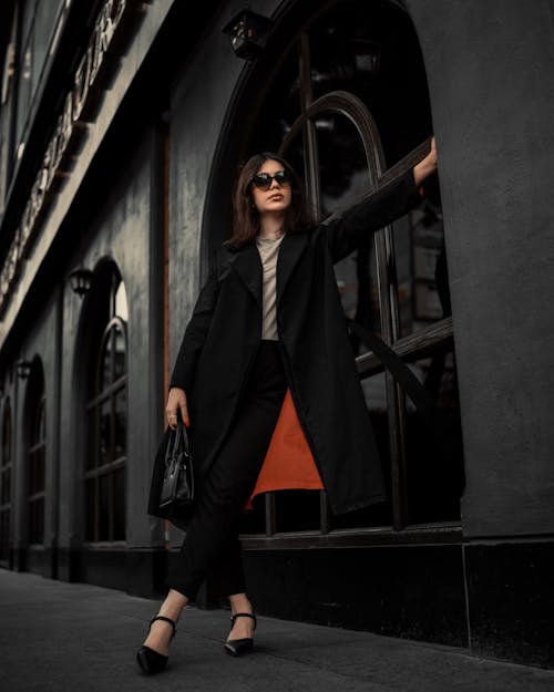 Elegant Woman with Sunglasses in Black Coat Posing on Sidewalk