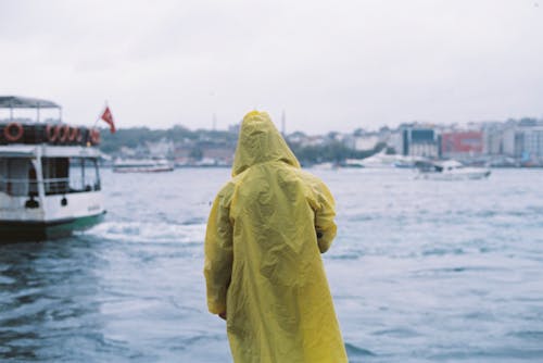 Person in Yellow Raincoat in Harbor