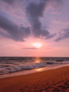 Stunning beach sunset with waves and pink sky, capturing tranquility and natural beauty.