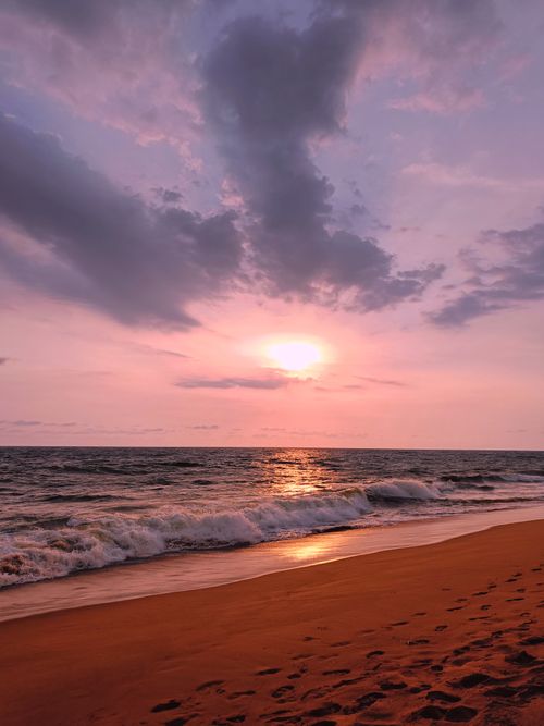 Free Stunning beach sunset with waves and pink sky, capturing tranquility and natural beauty. Stock Photo