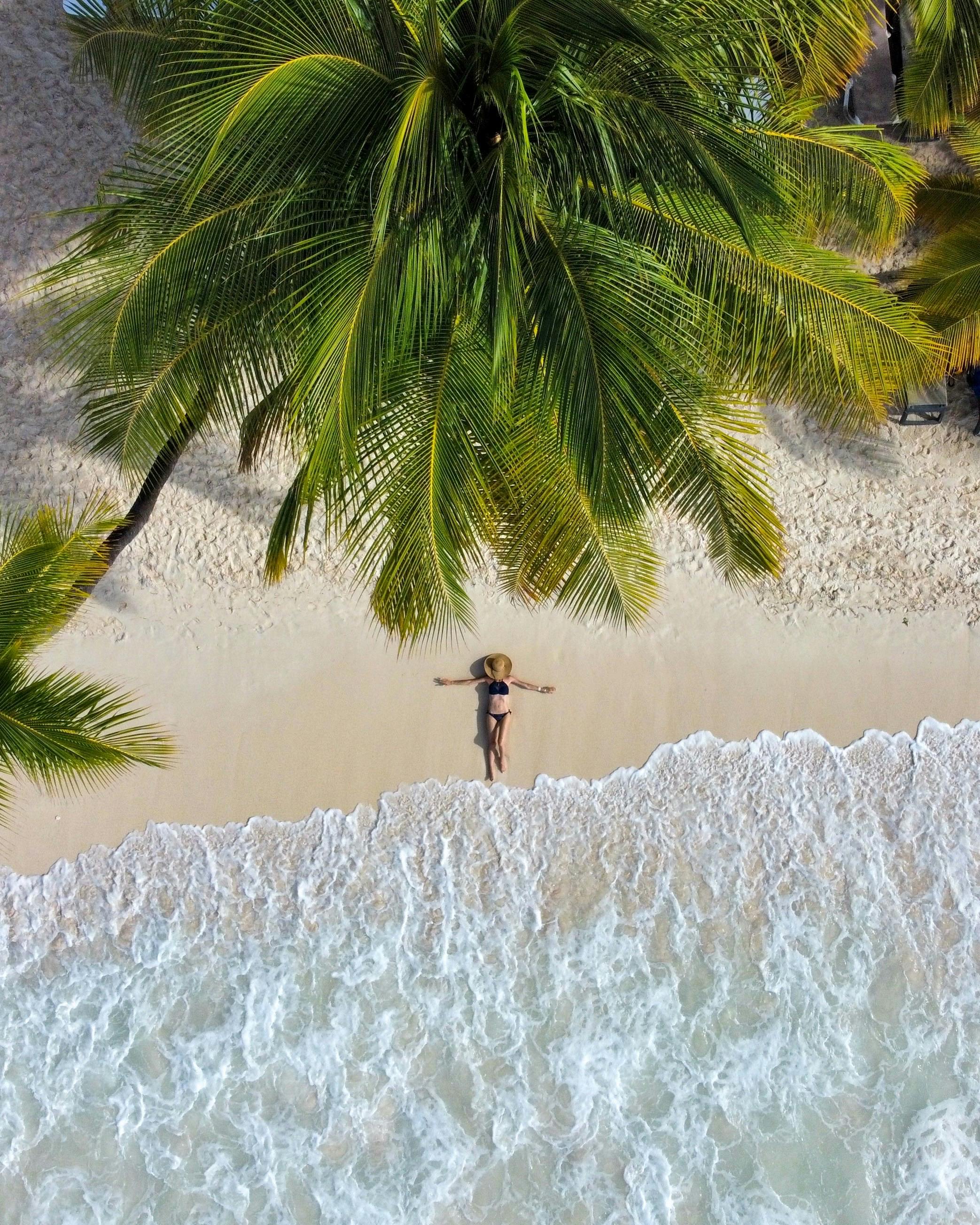 A woman relaxes on a tropical beach under palm trees in La Altagracia Province, Dominican Republic.