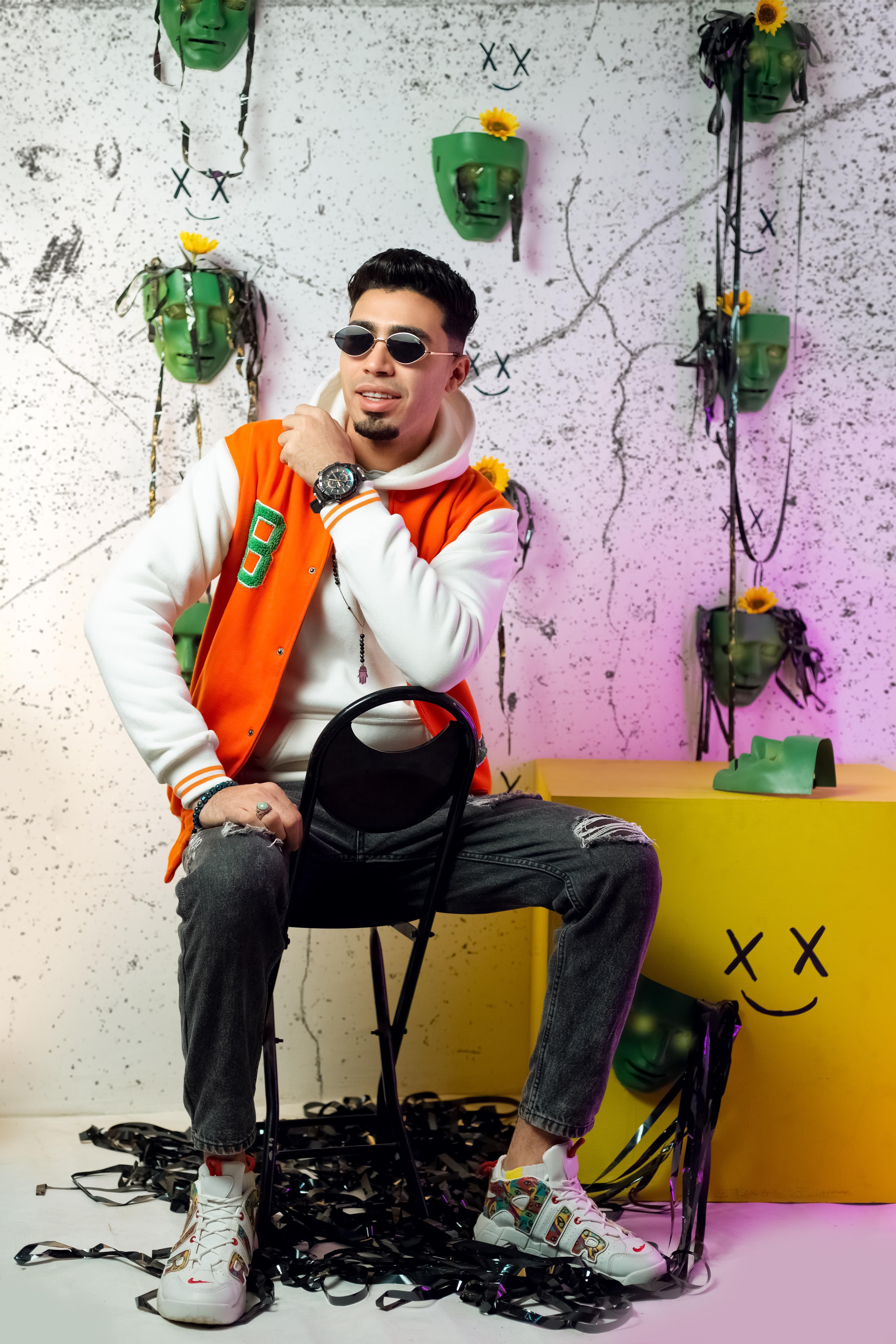 Man in vibrant outfit posing with artistic backdrop and wall art.