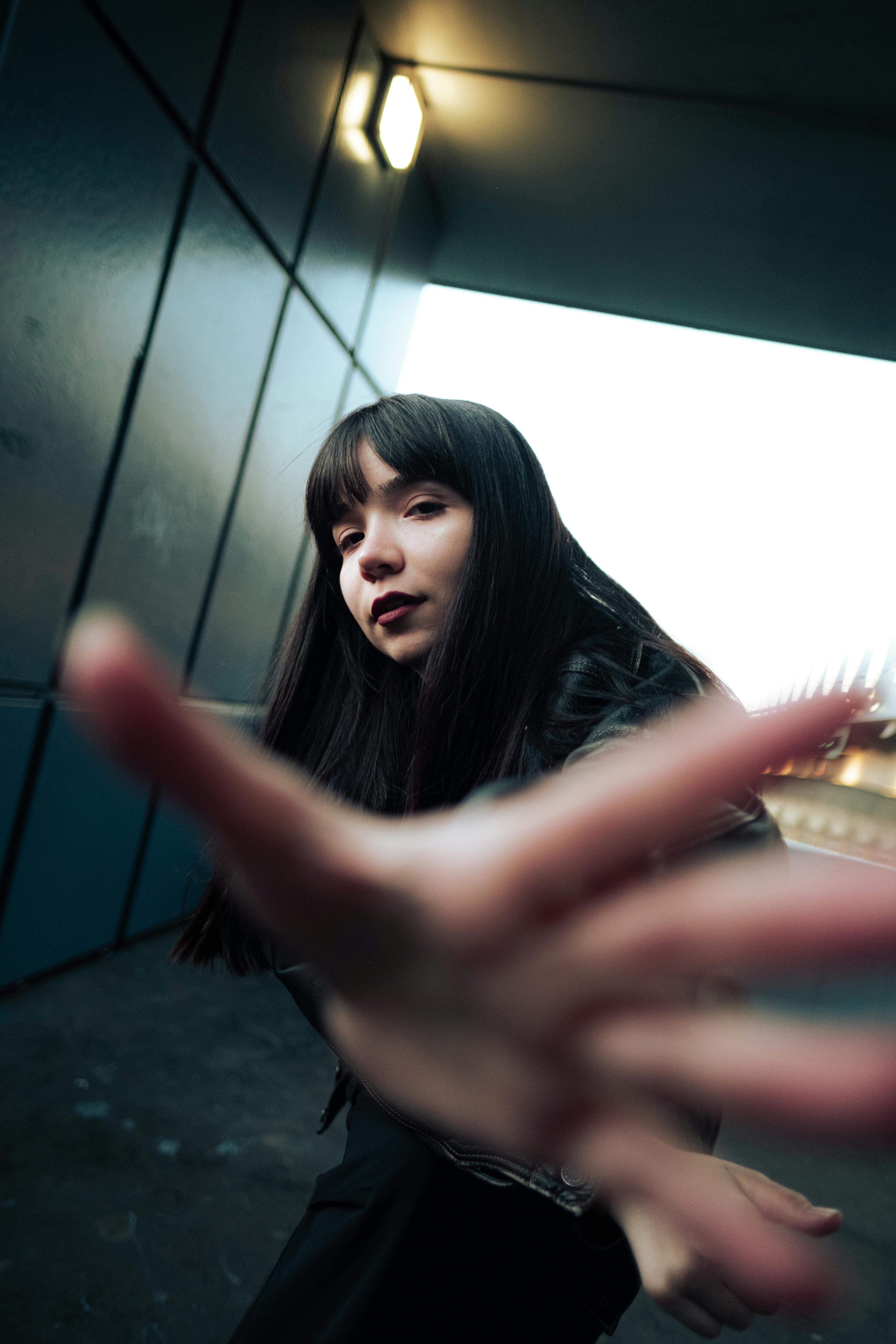 Artistic portrait of a young woman with dramatic lighting in a city tunnel.