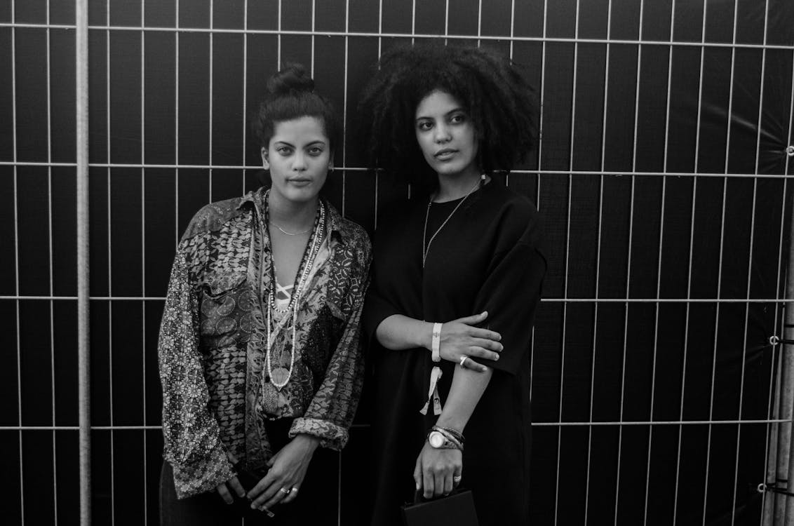 무료 강철봉 뒤에 서있는 2 명의 여성의 회색조 사진 스톡 사진